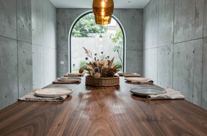 Table à manger en noyer massif dressée avec une vaisselle artisanale en grès, des serviettes en lin et un centre de table botanique séché dans un intérieur contemporain minimaliste